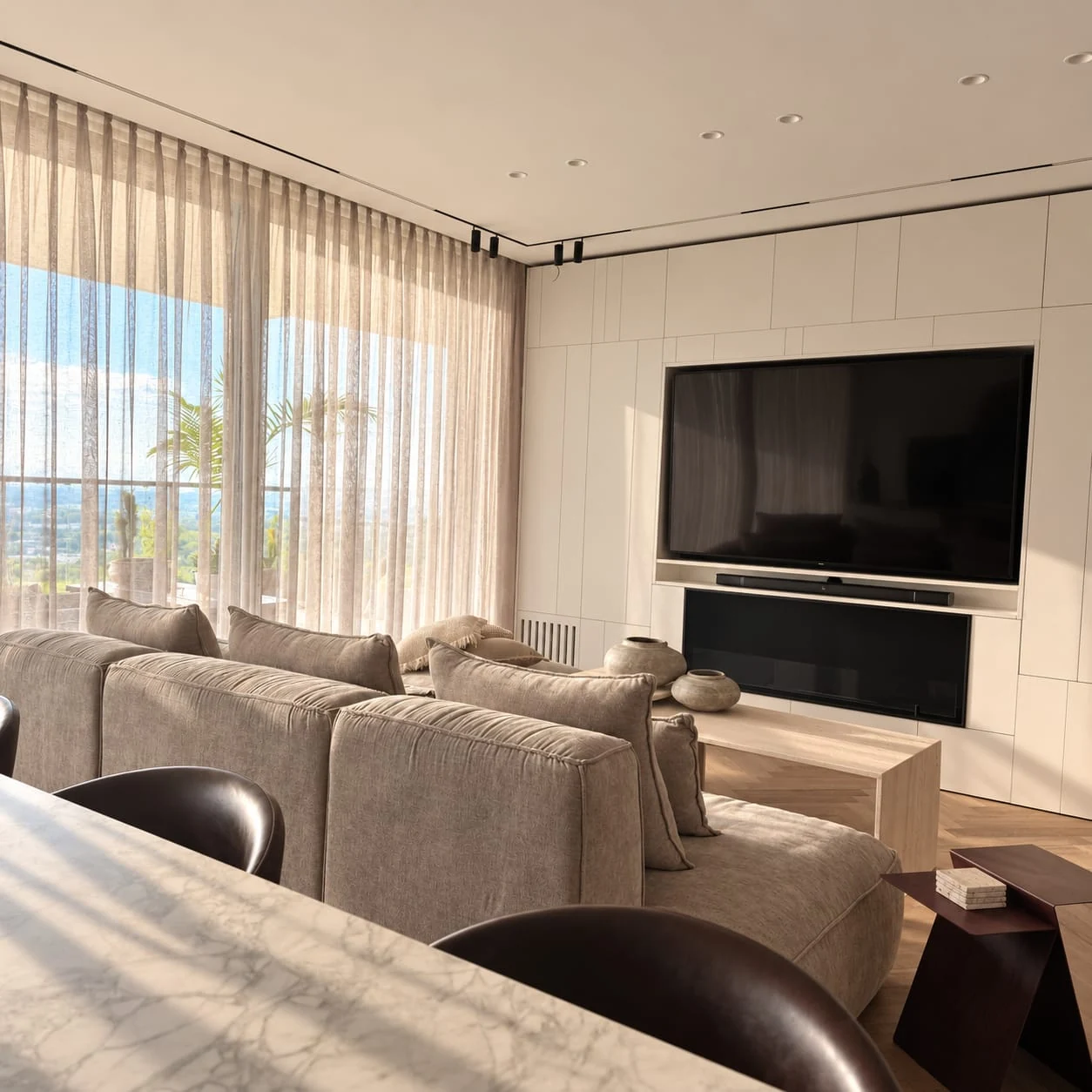 View from the kitchen towards the living room, television wall and sheer-curtained windows