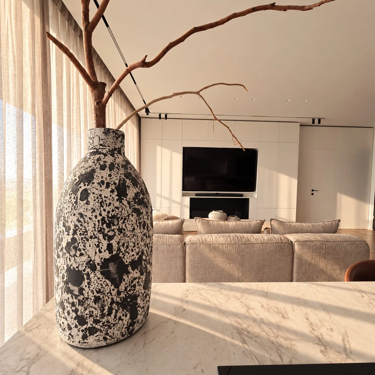 Close view of the island vase, with the sofa and television wall behind