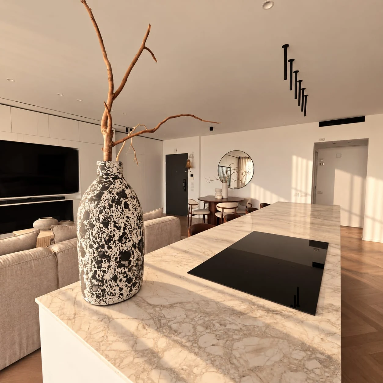 Pale island surface, black hob and a vase facing the living space