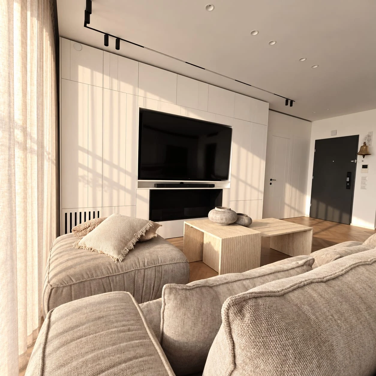 Sofa and stone-toned tables facing the television wall and pale cabinetry