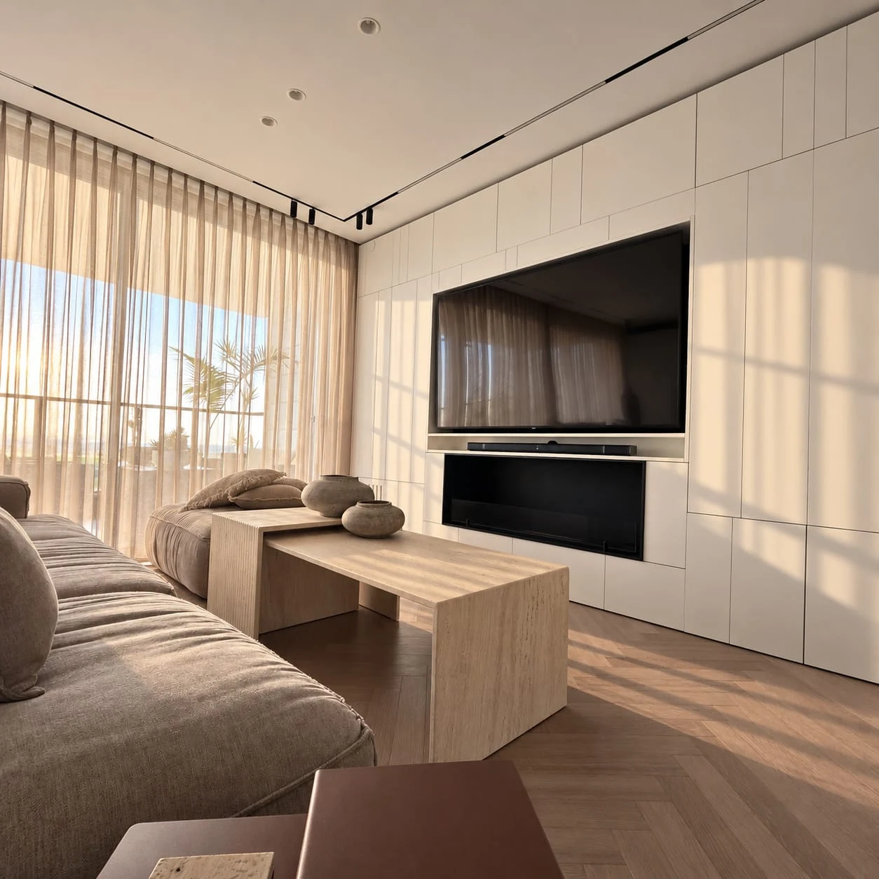 Side-lit living room with corner windows and a dark television recess