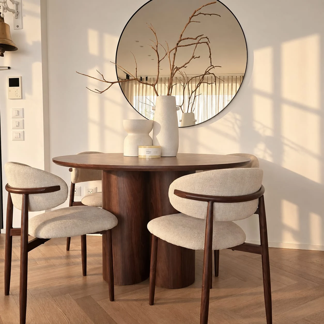 Sunlit dining area with a round table and a mirror above