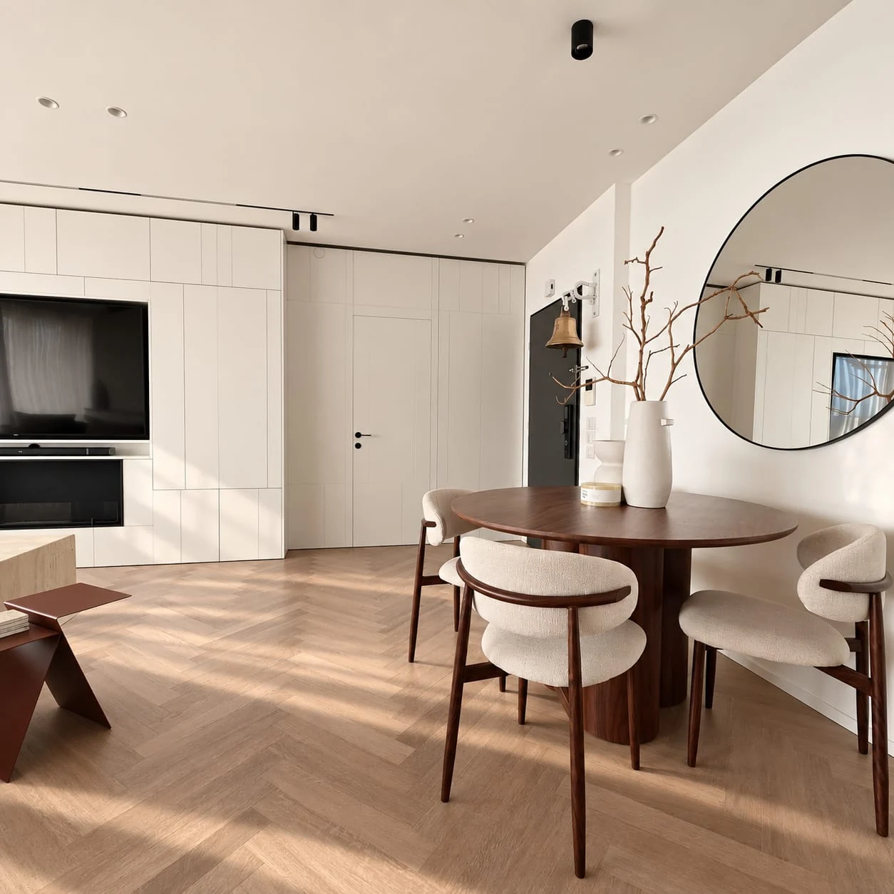 Dining table and round mirror beside the television wall and sofa
