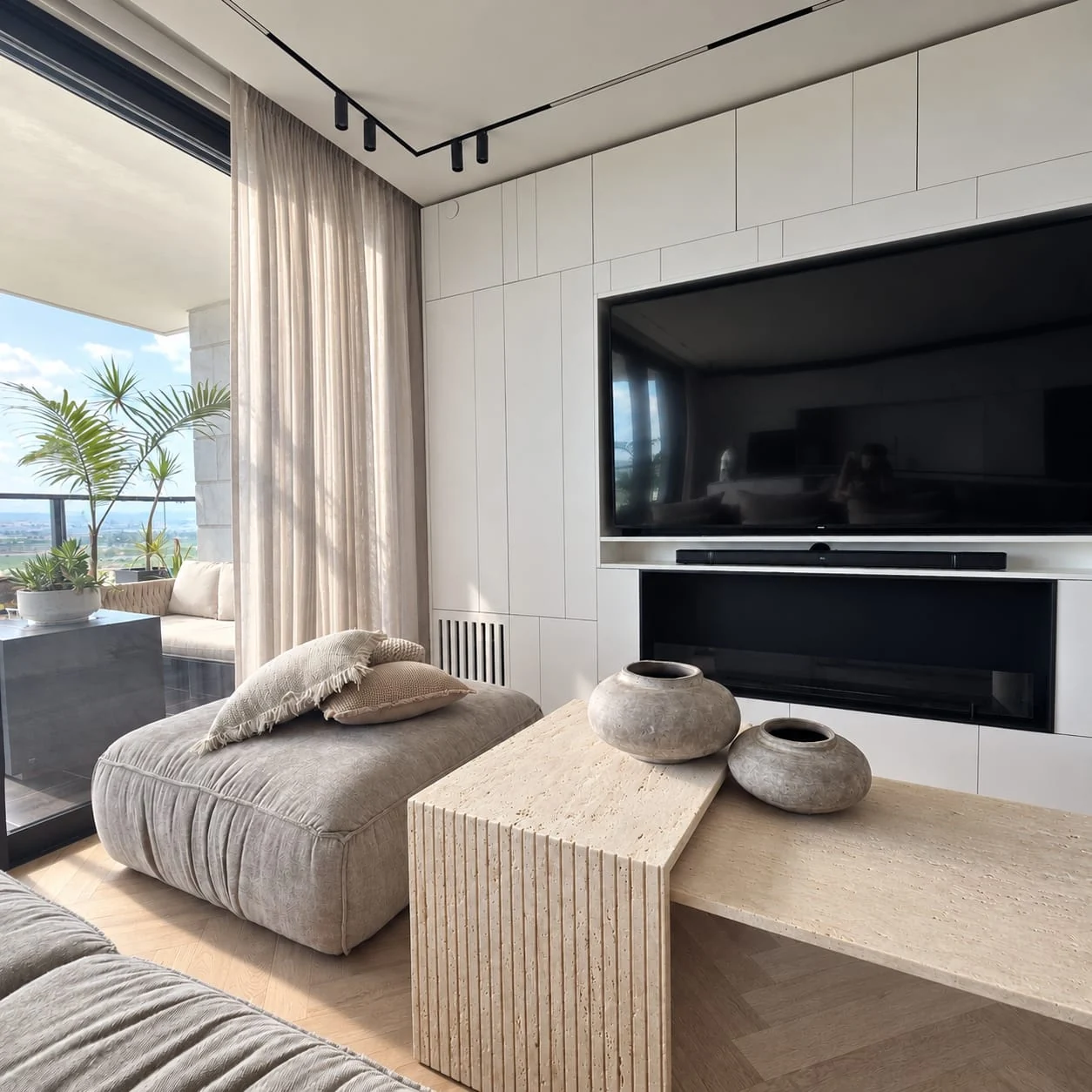Corner sofa, stone-toned tables and television wall beside the windows