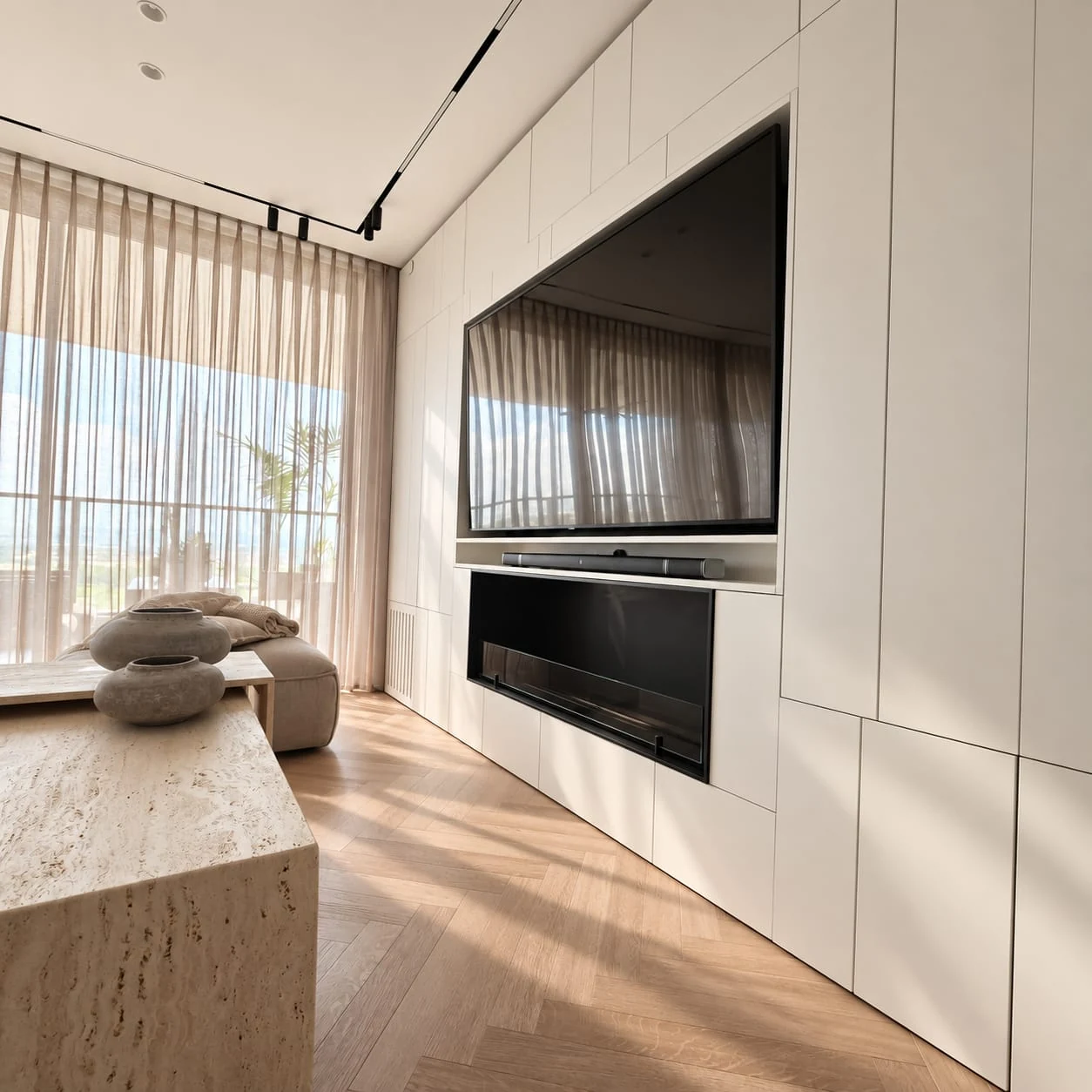 Television wall and pale cabinetry with living-room tables in the foreground