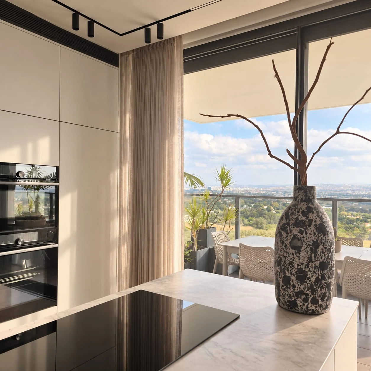 Hob and vase at the window end of the island facing cabinetry and ovens